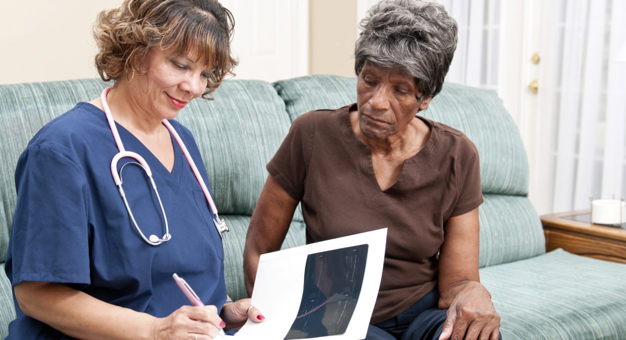 Professional African American Woman Heathcare Worker assisting an older African American woman in her home