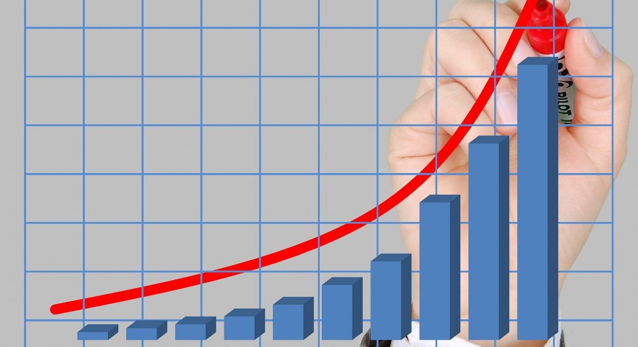 image of a bar graph with a hand superimposed drawing a red line of growth with a marker